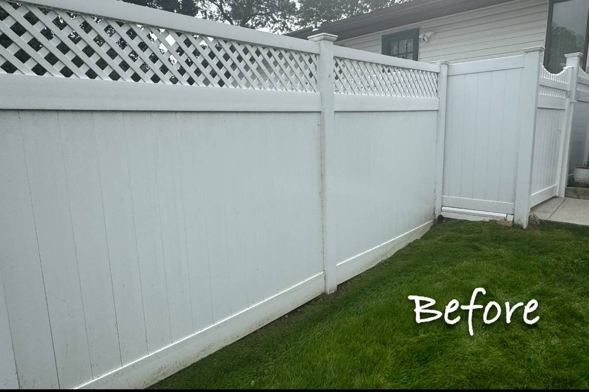 A dingy vinyl fence covered in mildew and grime before pressure and soft washing