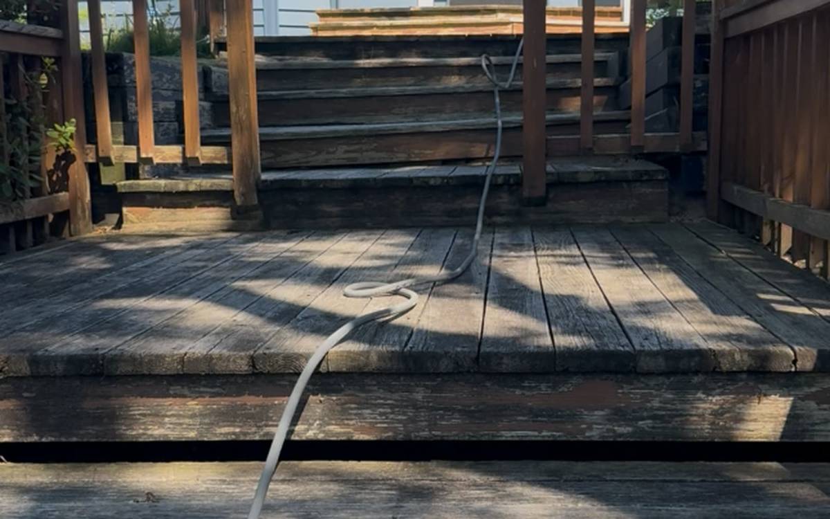 A weathered untreated backyard deck before pressure and soft washing